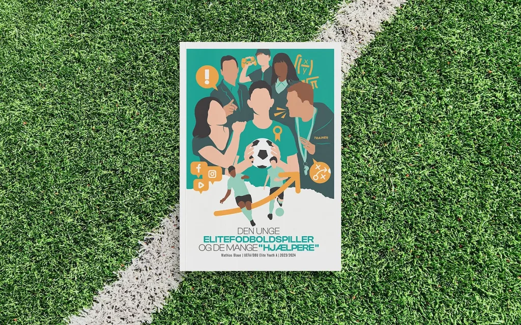 Ein Exemplar der Elitefußball Arbeit liegt auf dem Rasen eines Fußballfeldes.