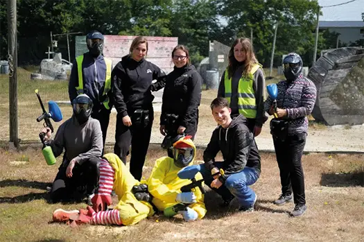 Ein Gruppenfoto von 8 Personen mit Paintball-Waffen. Kalle trägt ein Hahnenkostüm.